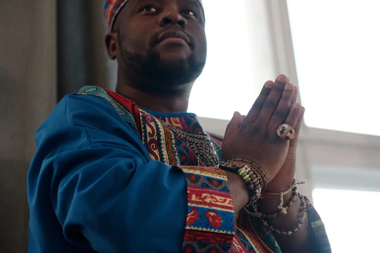 Person in traditional wear praying indoors, expressing cultural faith and spirituality.